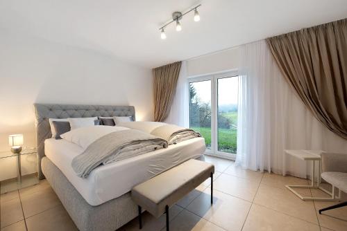 a white bedroom with a large bed and a window at Ferienwohnung Talblick in Stockach