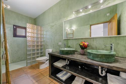a bathroom with two green sinks and a toilet at Can Marsá de Baix in Santa Eularia des Riu