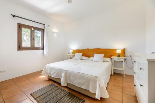 a white bedroom with a bed and a window at Can Marsá de Baix in Santa Eularia des Riu