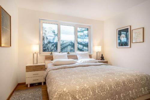 a bedroom with a large bed with two windows at Ländle Lodge bei Bregenz in Langen bei Bregenz
