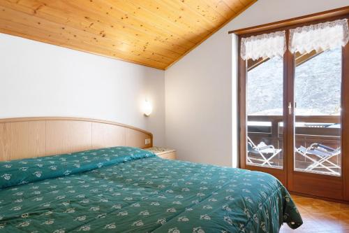 a bedroom with a bed and a large window at cèsa Maria Suen in Canazei