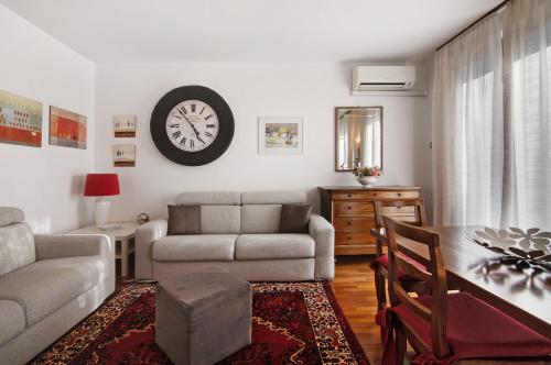 a living room with a couch and a clock on the wall at Apartment Bossi View in Chiavenna