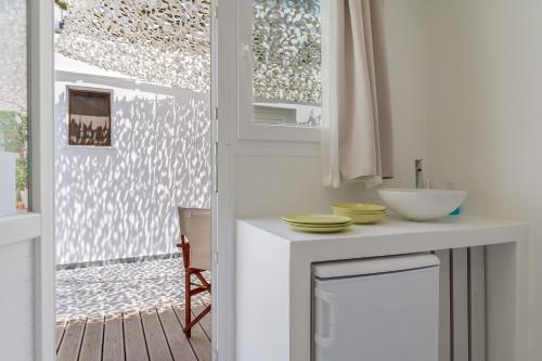 a white kitchen with a sink and a window at A Tinian Room 4 in Tinos