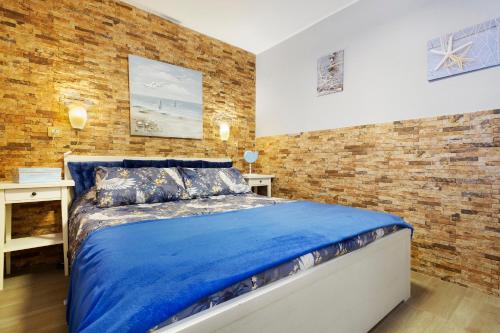 a bedroom with a blue bed and a brick wall at Plus Romance in Puerto del Carmen