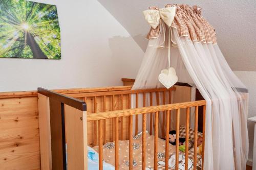 a baby crib with a canopy in a room at Naturhäusle Oberschwaben in Ebersbach-Musbach