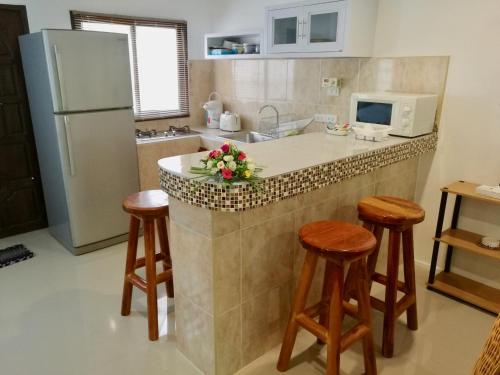 a kitchen with a counter with stools and a refrigerator at Soleil D'asie Residence in Chaweng Noi Beach