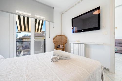 a white bedroom with a large bed and a flat screen tv at Apartment with spa and bbq in El Vendrell