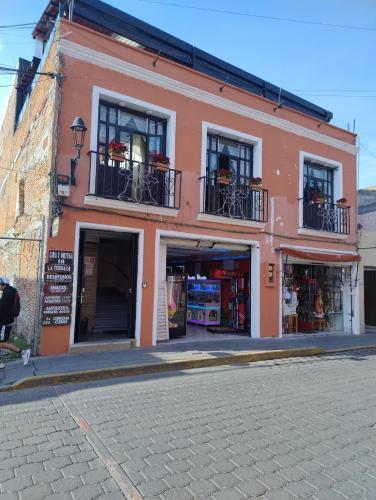 a red building with windows and balconies on a street at Hotel Boutique Las Campanas in Tlaxcala de Xicohténcatl