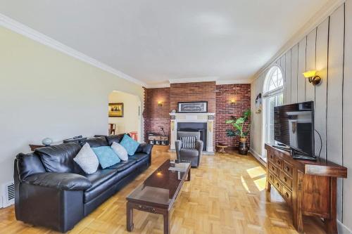 a living room with a black leather couch and a fireplace at Spacious 2br Near Ocean & Sutro Heights Park in San Francisco