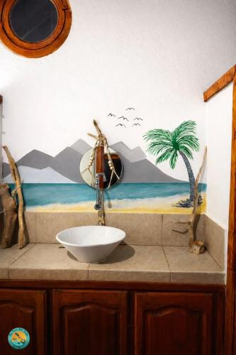 a bathroom sink with a palm tree mural on the wall at Ny Fano Kite Lodge in Ivovona