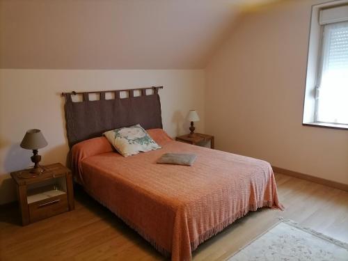 a bedroom with a bed with an orange blanket and a window at Le Gite du Champ de la Croix in Subligny