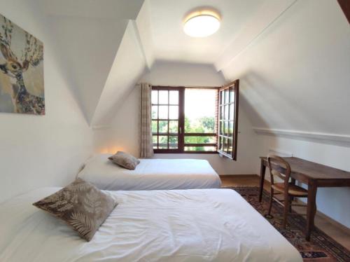 two beds in a room with a desk and a window at Le Relais de Chasse in Eu