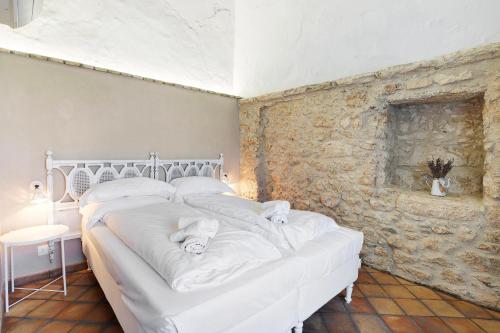 a white bed in a room with a stone wall at Casa Virginia - Corbezzolo in Orco Feglino