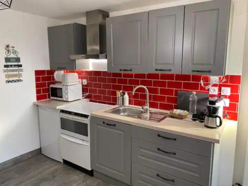 Una cocina con fregadero y una pared de ladrillo rojo. en La Noisette, en Équemauville