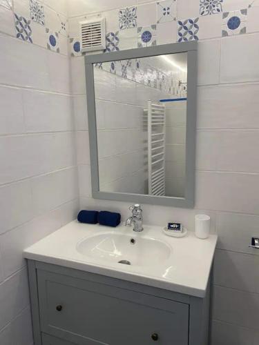 a white bathroom with a sink and a mirror at La Noisette in Équemauville