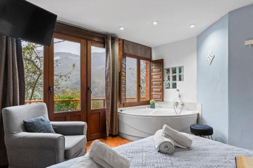 a bathroom with a tub and a bed and a chair at El Ablanu, jacuzzi y vistas in Proaza