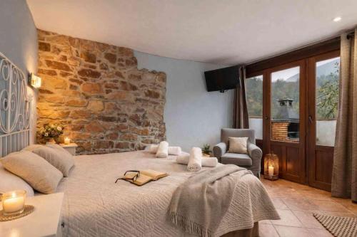 a bedroom with a large bed and a stone wall at El Ablanu, jacuzzi y vistas in Proaza