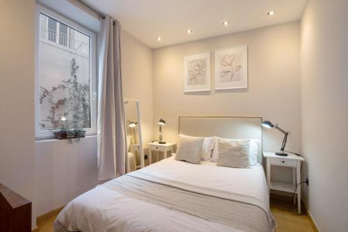 a bedroom with a bed with white sheets and a window at Casa Viola in Faro