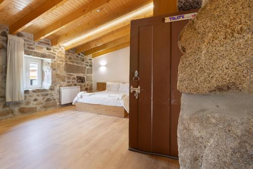 a bedroom with a bed and a stone wall at Casa da Marquinhas - Turismo Rural in Lama de Ouriço