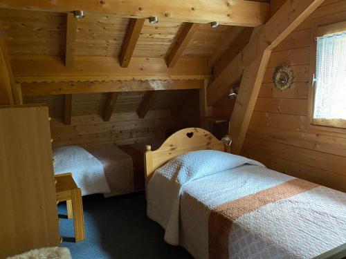 two beds in a room with wooden walls at Chalet 6p Confort - Le chevreuil in Verchaix