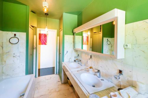a bathroom with two sinks and a mirror and green walls at Espace, Luxe, Calme Et Nature in Saint-Martin-de-Seignanx