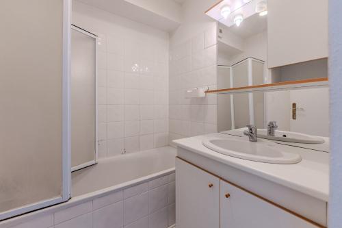 a white bathroom with a sink and a bath tub at Appartement proche plage Parentis in Parentis-en-Born