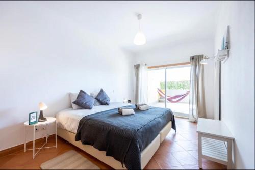 a white bedroom with a bed and a window at Casa Cláudia - Cond do Mar in Lagos