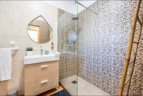 a bathroom with a shower with a sink and a mirror at Casa Cláudia - Cond do Mar in Lagos
