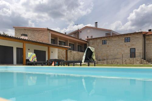 a swimming pool in front of a house at Casa da Marquinhas - Turismo Rural in Lama de Ouriço