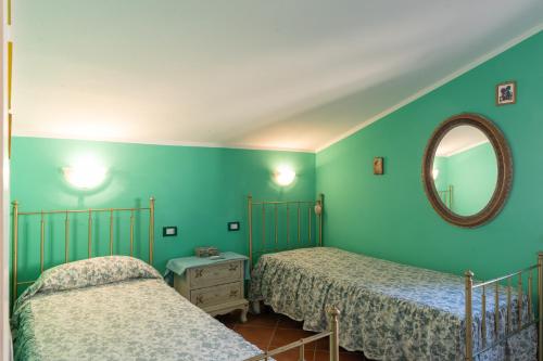 two beds in a room with green walls and a mirror at Casa Delle Pomelie in Trappeto