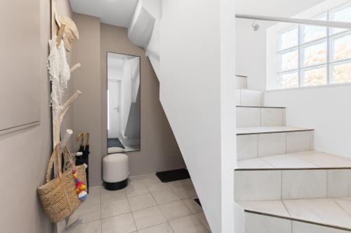 a white hallway with a staircase and a mirror at Fewo Bergfeld in Mosbach