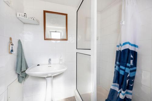 a white bathroom with a sink and a shower at Abrigo do Pescador in Aljezur