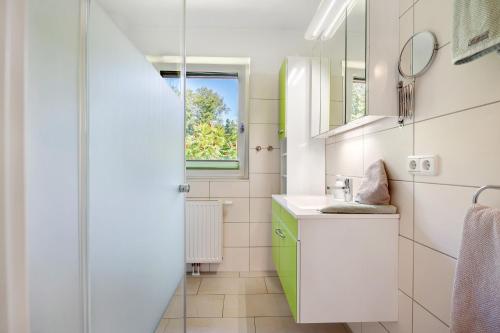 a white bathroom with a sink and a window at Fewo Birkenallee - Apfel in Deinste