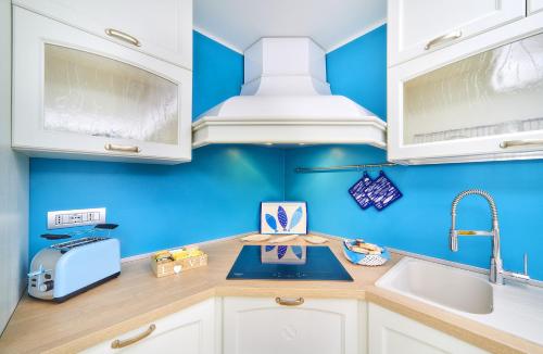 a kitchen with white cabinets and a blue wall at El Lavandee in Varenna