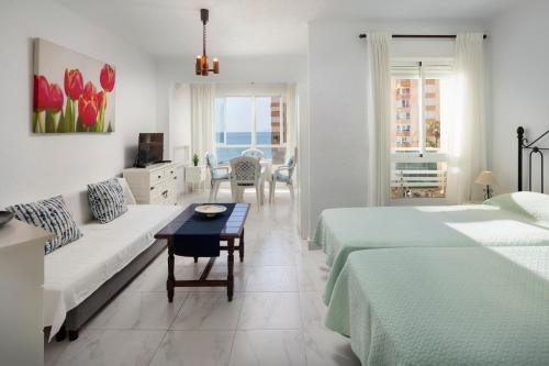 a bedroom with two beds and a couch and a table at Estudio Bloque 80 in Torrox