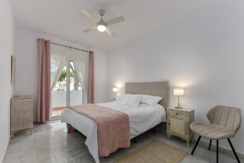 a bedroom with a bed and a chair and a window at Penthouse Jacaranda in Estepona