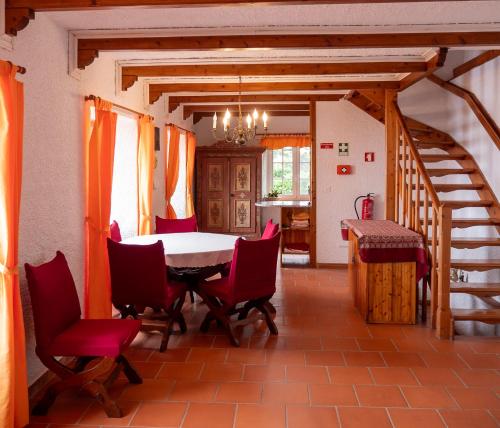a dining room with a table and red chairs at Villa Lomba Bela Vista in Lomba