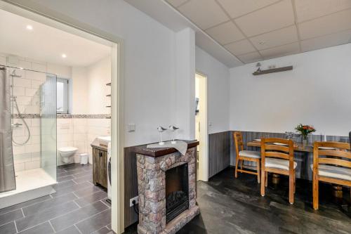 a bathroom with a fireplace and a dining room with a table at Klönstuv in Breklum