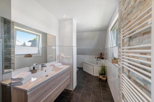a bathroom with a sink and a tub and a window at Haus Seeblick in Göhren-Lebbin