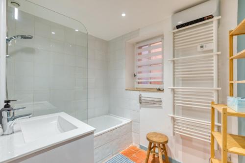 a white bathroom with a sink and a tub at La Reine in Béziers