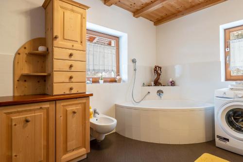 a bathroom with a tub and a sink and a washing machine at Ferienwohnung Toni II in Siusi