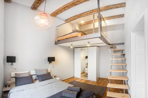 a loft bedroom with a bed and a staircase at Gertrudy Old Town Apartments in Kraków