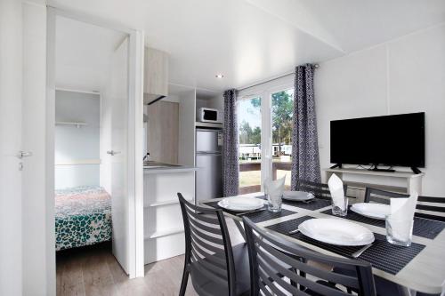 a dining room with a table with chairs and a television at Bungalow T2 I - 15 Min From Nazaré in Pataias
