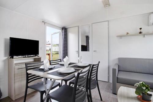 a dining room with a table and chairs and a television at Bungalow T2 I - 15 Min From Nazaré in Pataias