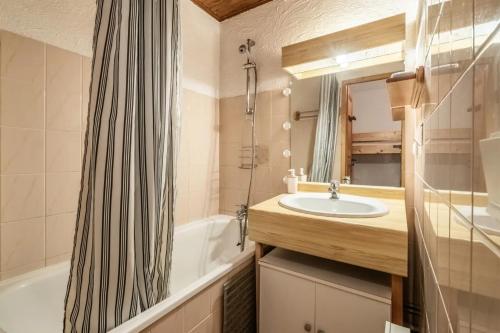 a bathroom with a sink and a tub and a mirror at Duo d'appartements - Chatel in Châtel