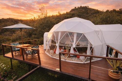 a white iguana tent on a deck at sunset at Glamping Claro de Luna in Guatavita