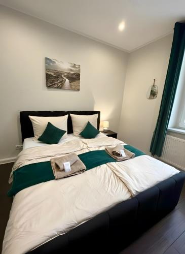 a bedroom with a large bed with green and white pillows at Altstadt-Oase 2 in Cottbus
