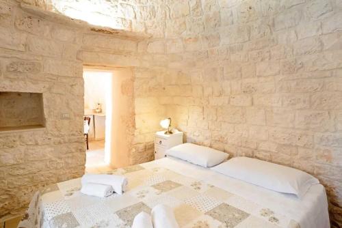 a bedroom with a large bed in a stone wall at Trullo Pesco in Martina Franca