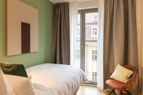 a bedroom with a bed and a window and a chair at AlegraStay Apartments - Dresden City in Dresden