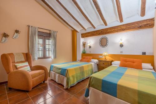 a bedroom with two beds and a chair at Romero in Hinojares